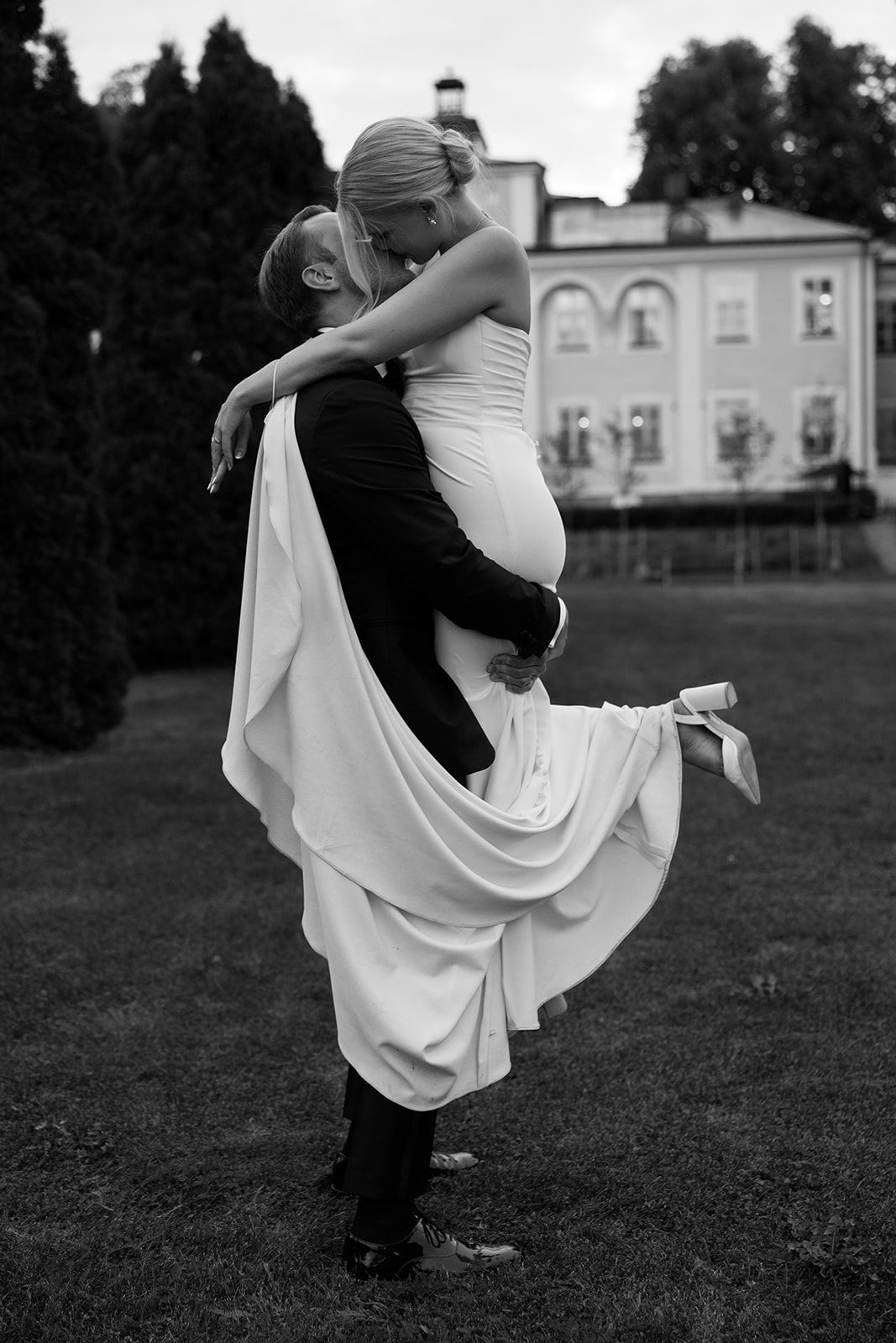 A romantic black and white photo series showing a couple dancing together on a grassy lawn with elegant flowing movement.