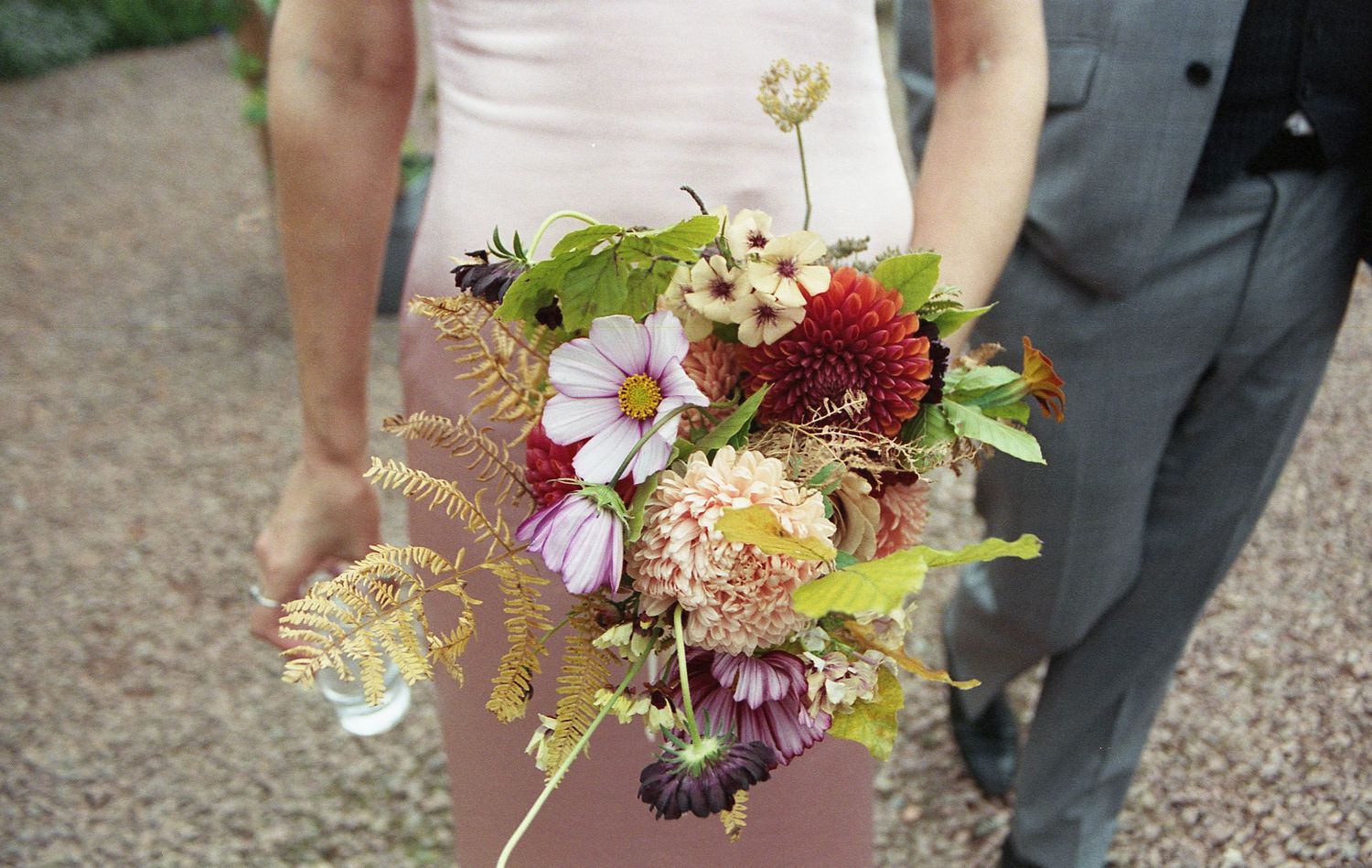 A collection of wedding bouquets featuring colorful wildflowers and delicate blooms in a rustic outdoor setting.