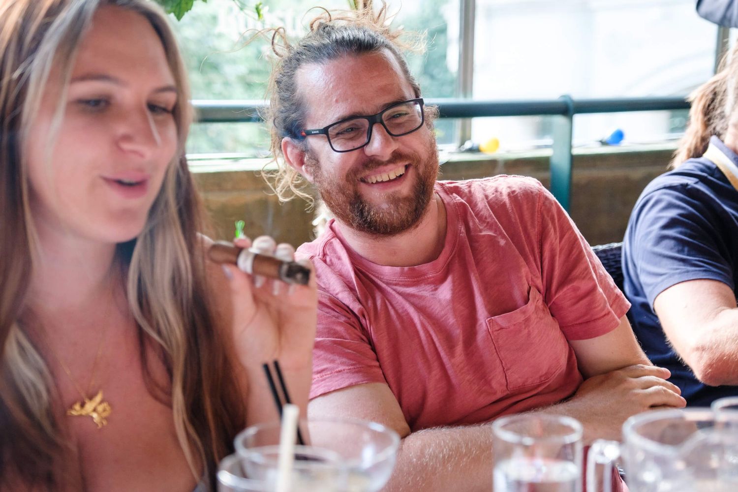 Friends gathered around a table sharing drinks and conversation in a bright restaurant setting.
