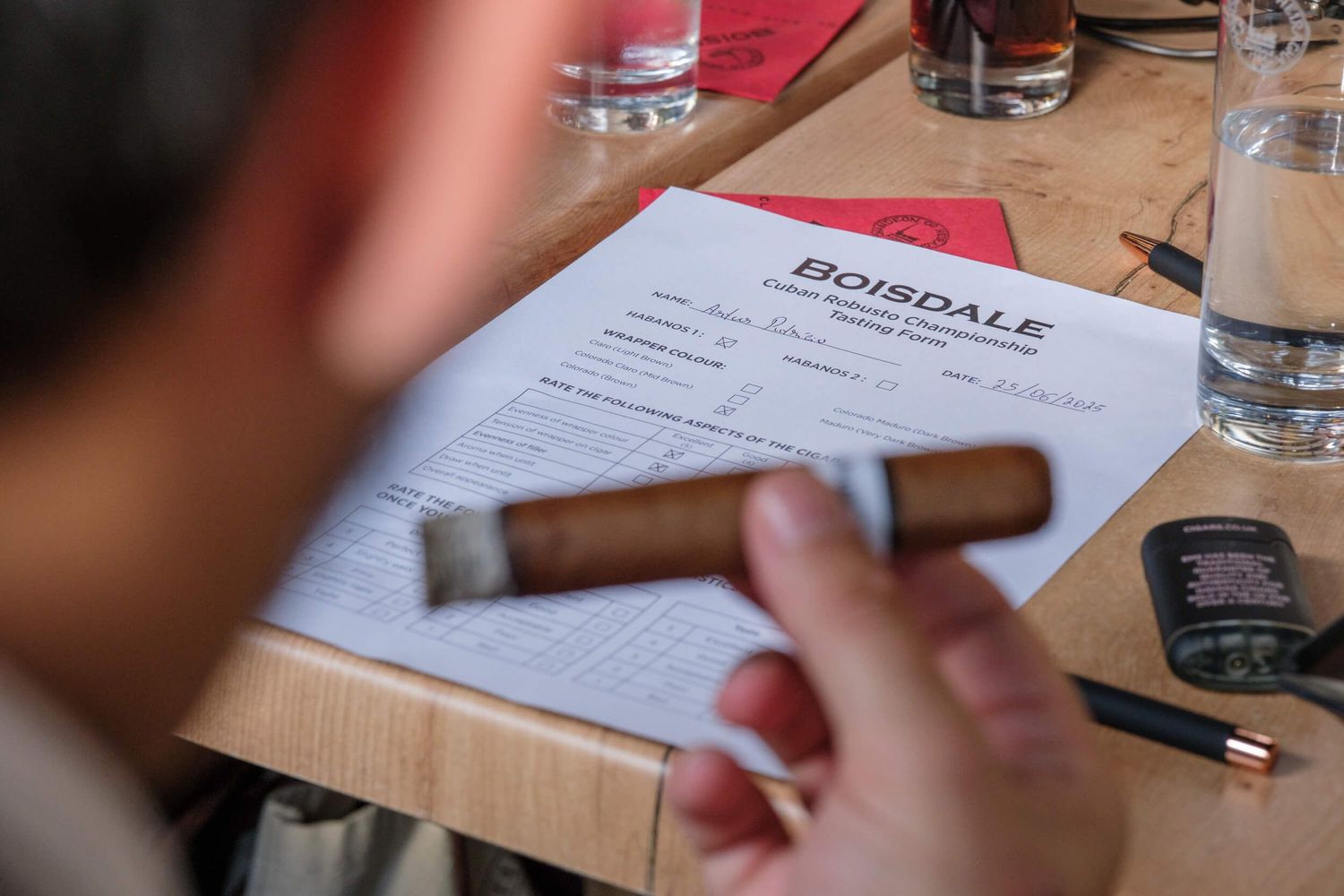 Menu and drinks on a wooden restaurant table with someone holding a pen.