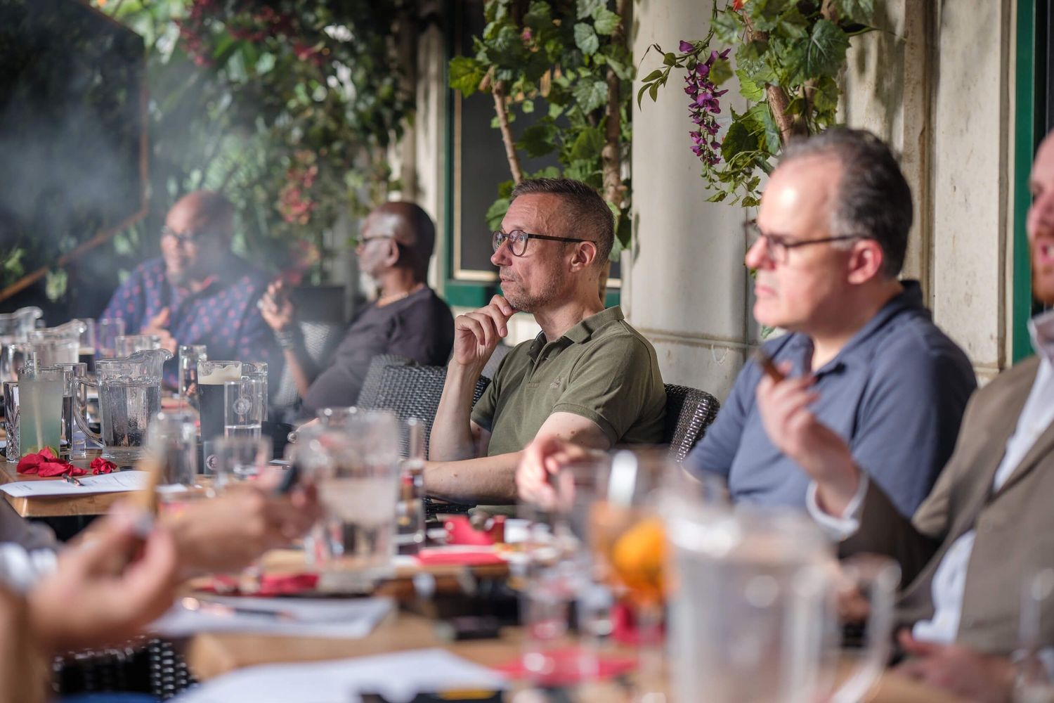 People enjoying an outdoor meal at a restaurant patio with drinks and conversation.