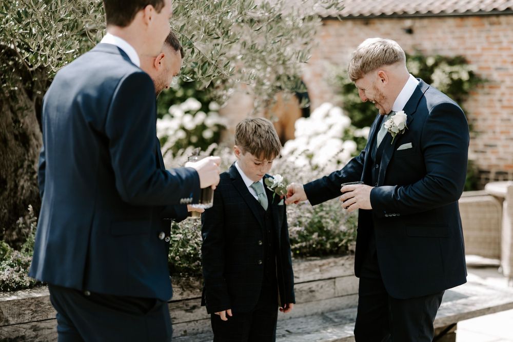 Groomsmen in navy suits share a candid moment while getting ready for a wedding ceremony.