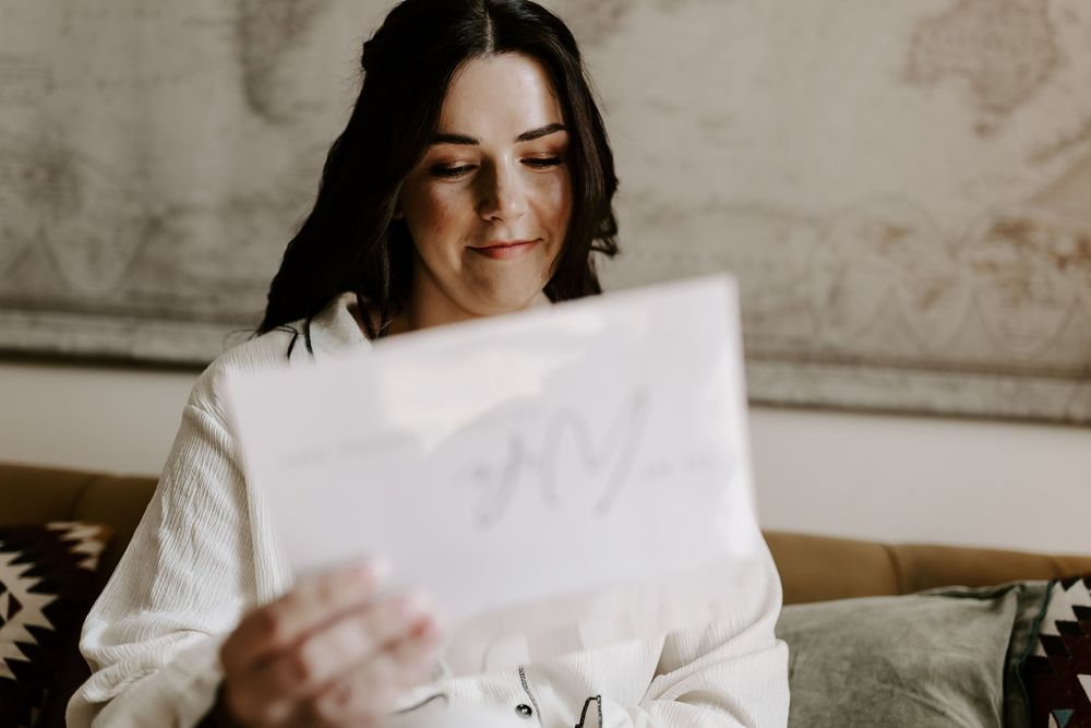 Multiple images show someone in white holding and reading papers against a neutral background.