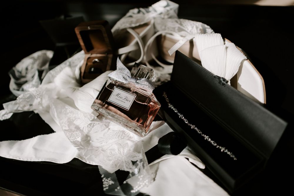 A perfume bottle rests on crumpled white tissue paper next to a black box on a dark surface.