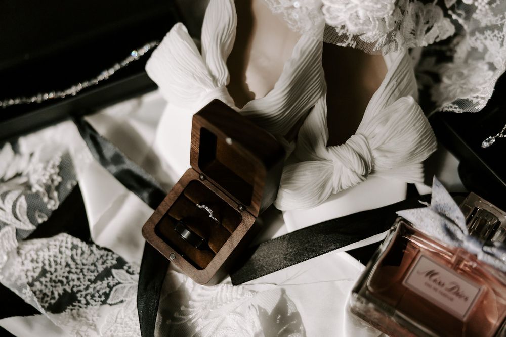 Wedding details featuring vintage perfume bottles and jewelry arranged artistically in black and white.