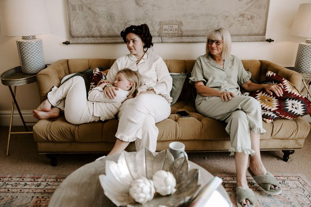 Five connected images show people in white outfits lounging on a beige couch in a modern living room setting.