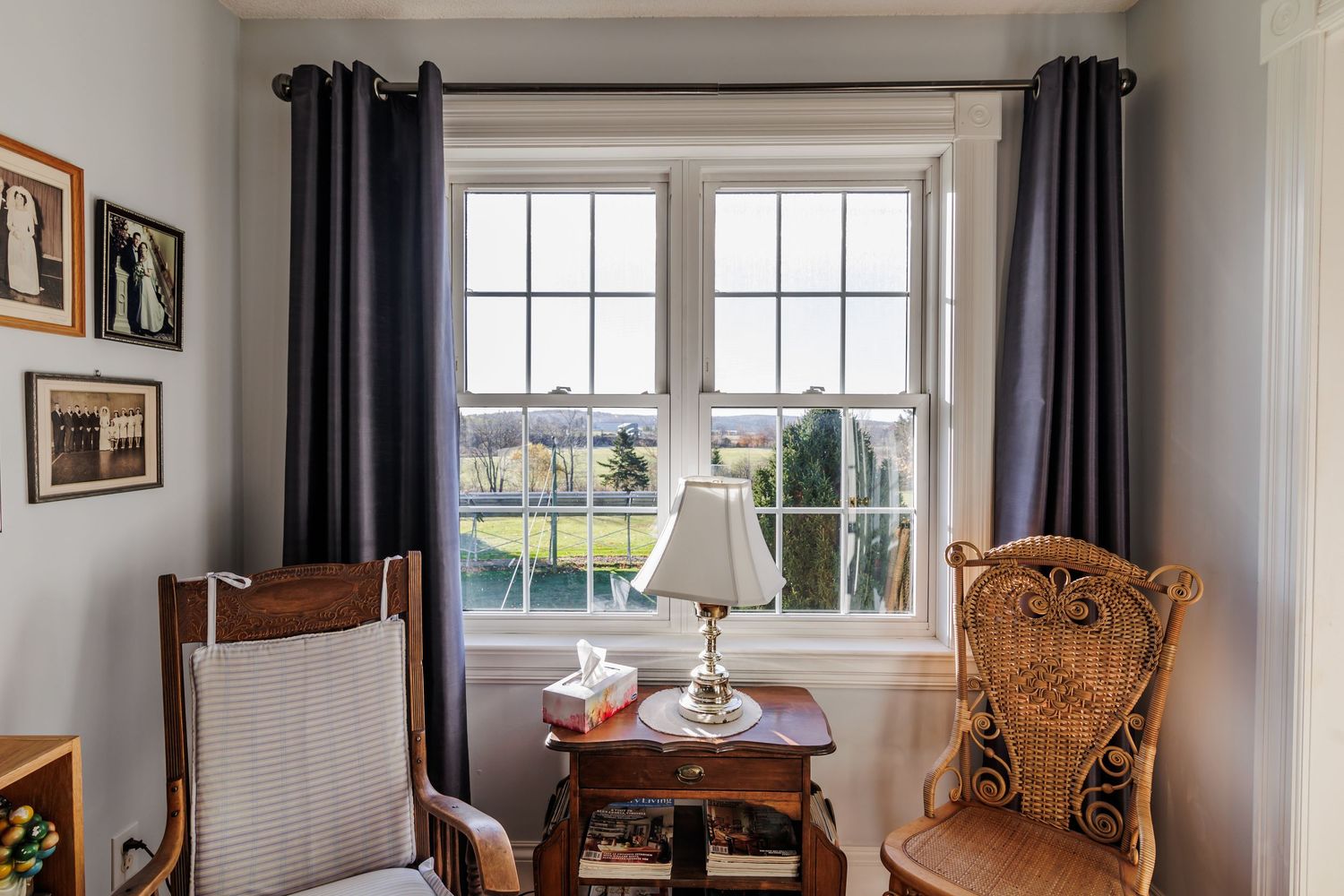 A panoramic view of a bright living room with wooden furniture, white walls, and large windows overlooking a garden.