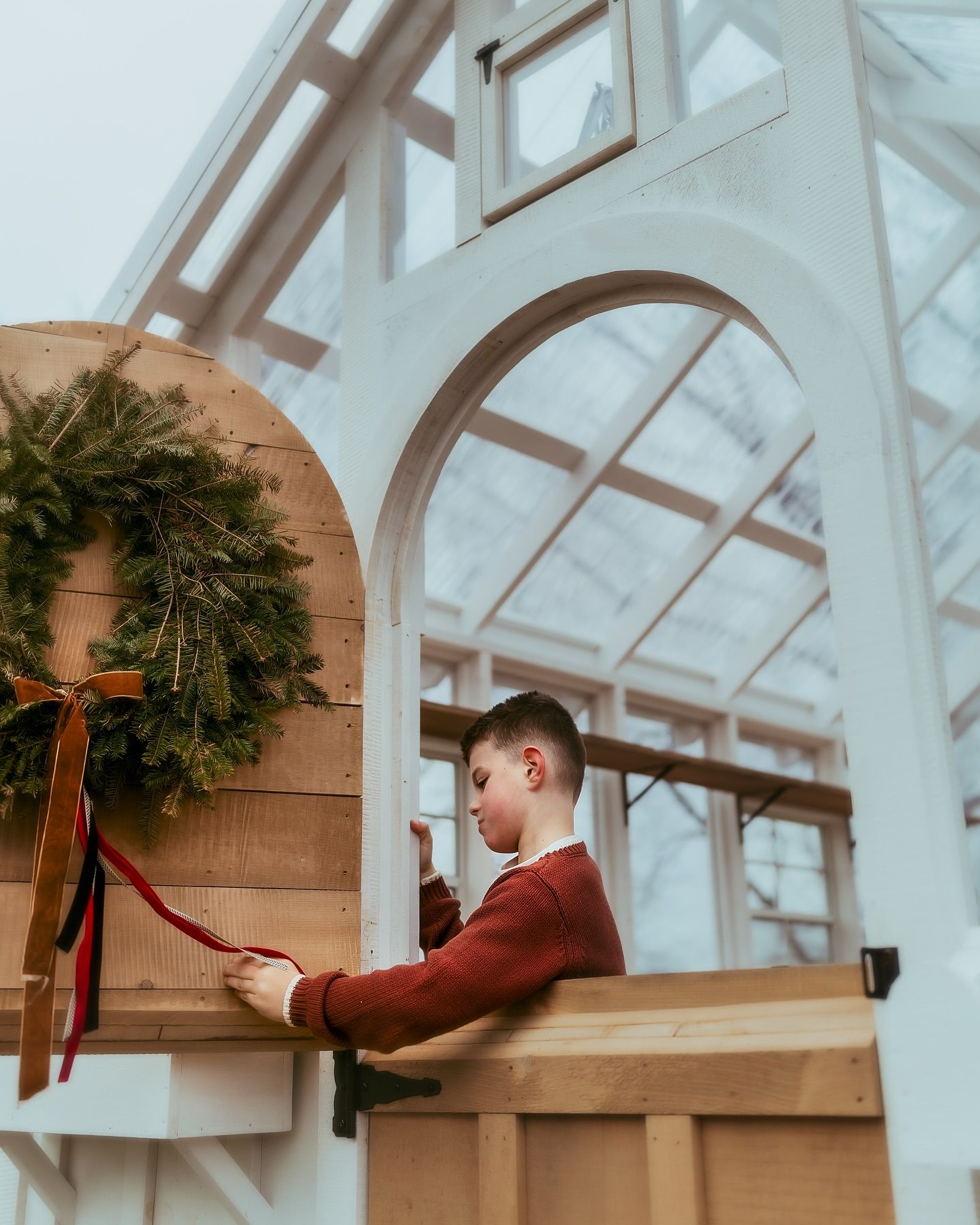 A progressive sequence of someone hanging a decorative holiday wreath with a red bow on a white wall.