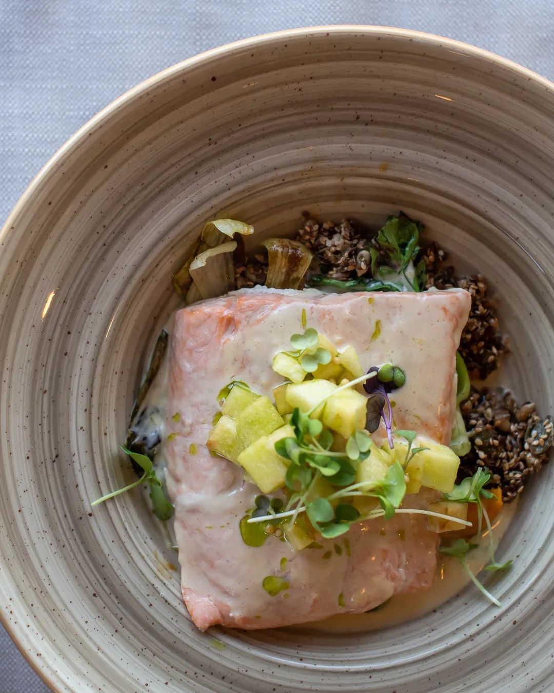 Close-up overhead shot of a beautifully plated dish topped with fresh green garnish.
