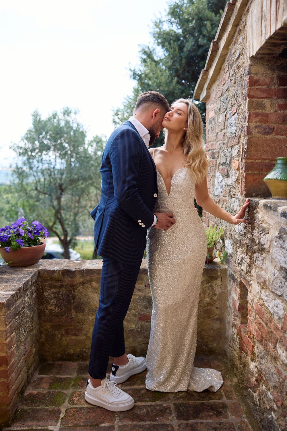 Bride and groom share a romantic moment on a rustic stone terrace in Tuscany, Italy.