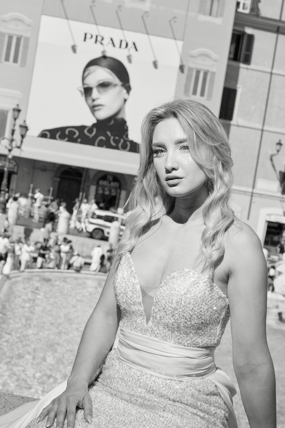Elegant blonde bride in a sparkling gown poses near the Spanish Steps with a Prada billboard behind her.