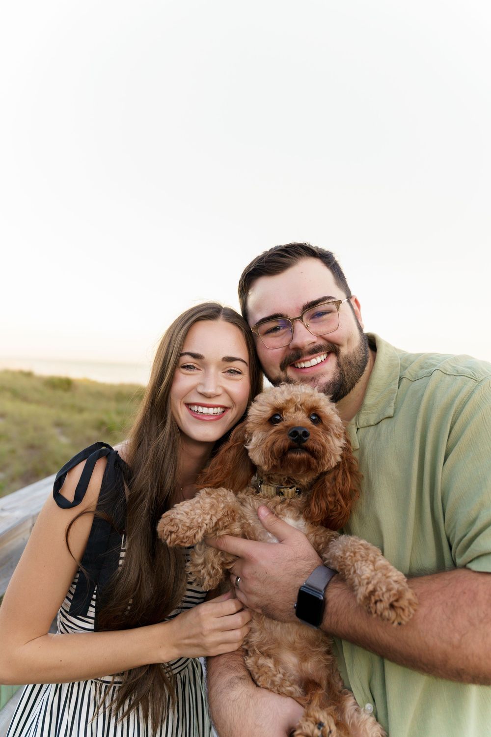 A couple poses for a series of four photos with their small brown dog showing affection and smiles outdoors.