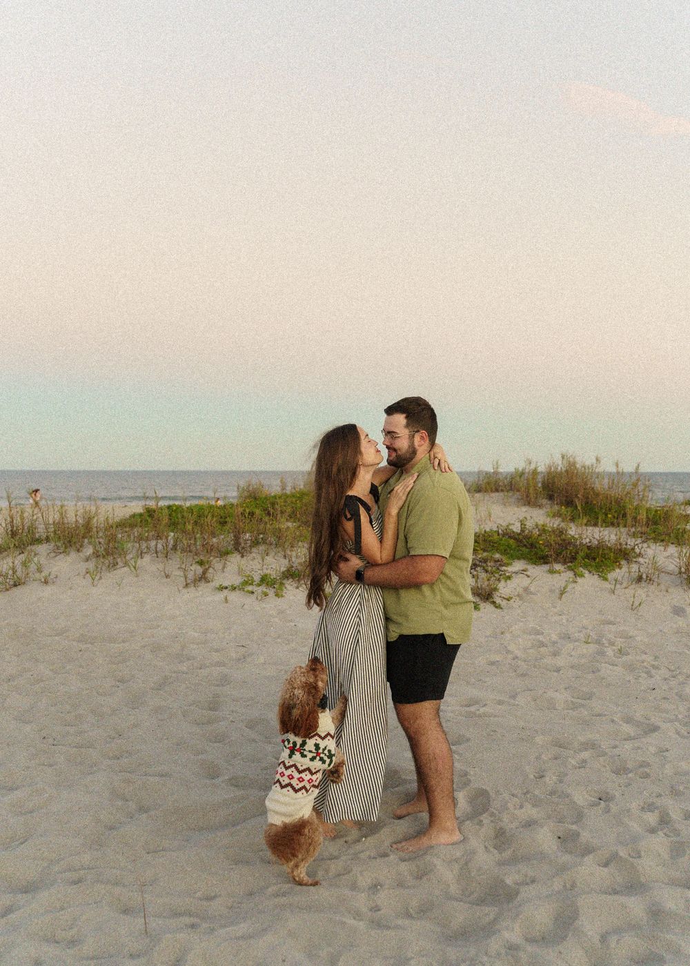 A couple shares romantic moments on a sandy beach at sunset in a series of connected photos.