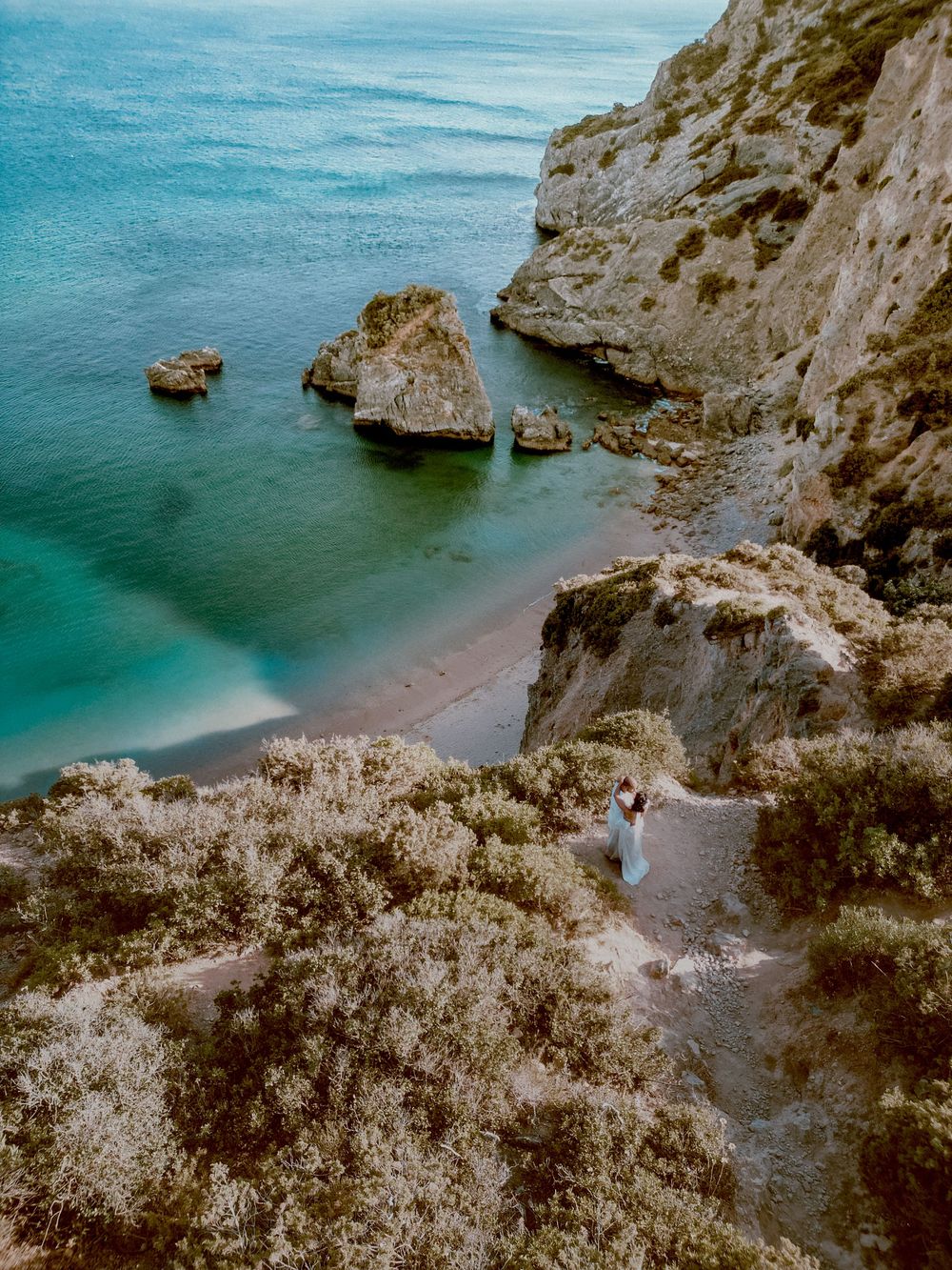 Coastal landscape with turquoise waters and rugged limestone cliffs along a secluded beach in Portugal.