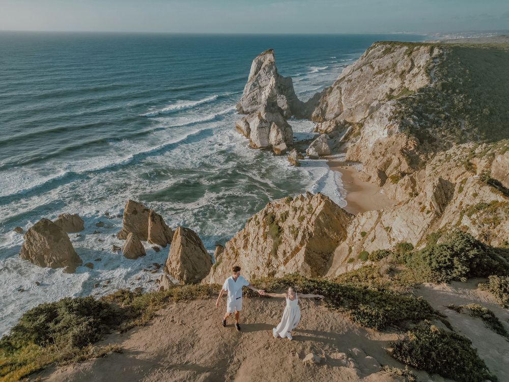 Rugged coastal cliffs meet crashing ocean waves along a dramatic Pacific coastline at sunset.