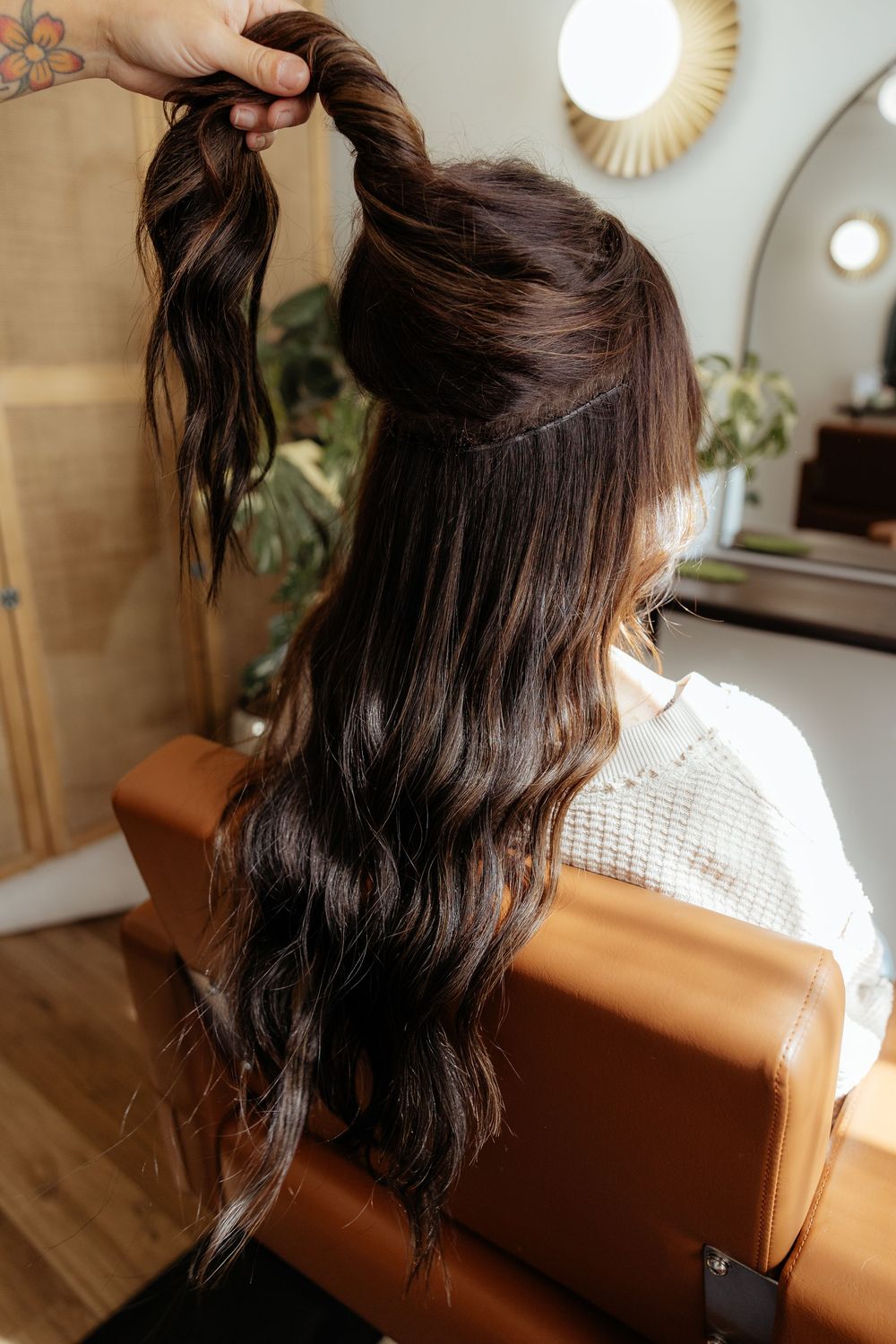 Back view of dark brown hair styled with loose waves against a bright interior setting.