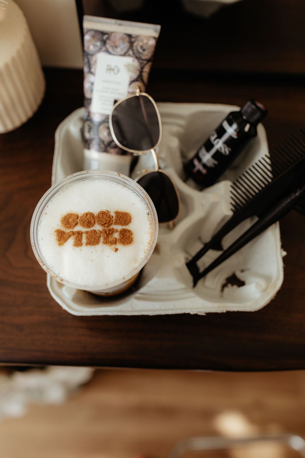 Close-up view of coffee art on white foam in a ceramic cup with brown lettering design.