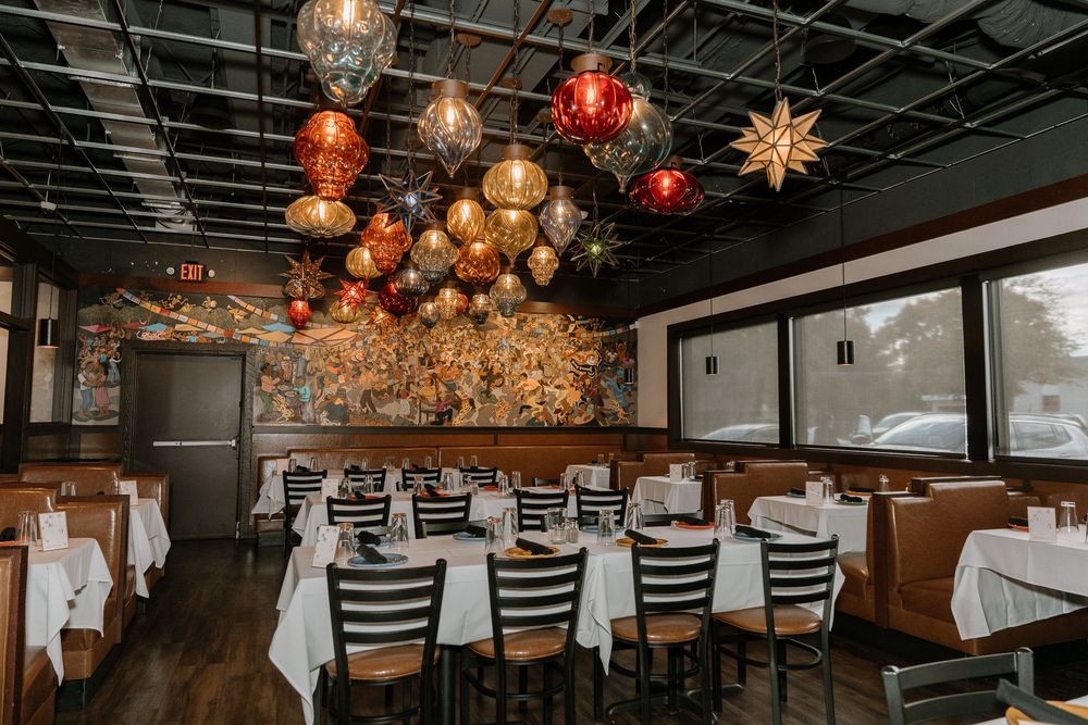 Elegant restaurant interior with hanging star-shaped light fixtures and white tablecloths creating an upscale dining atmosphere.