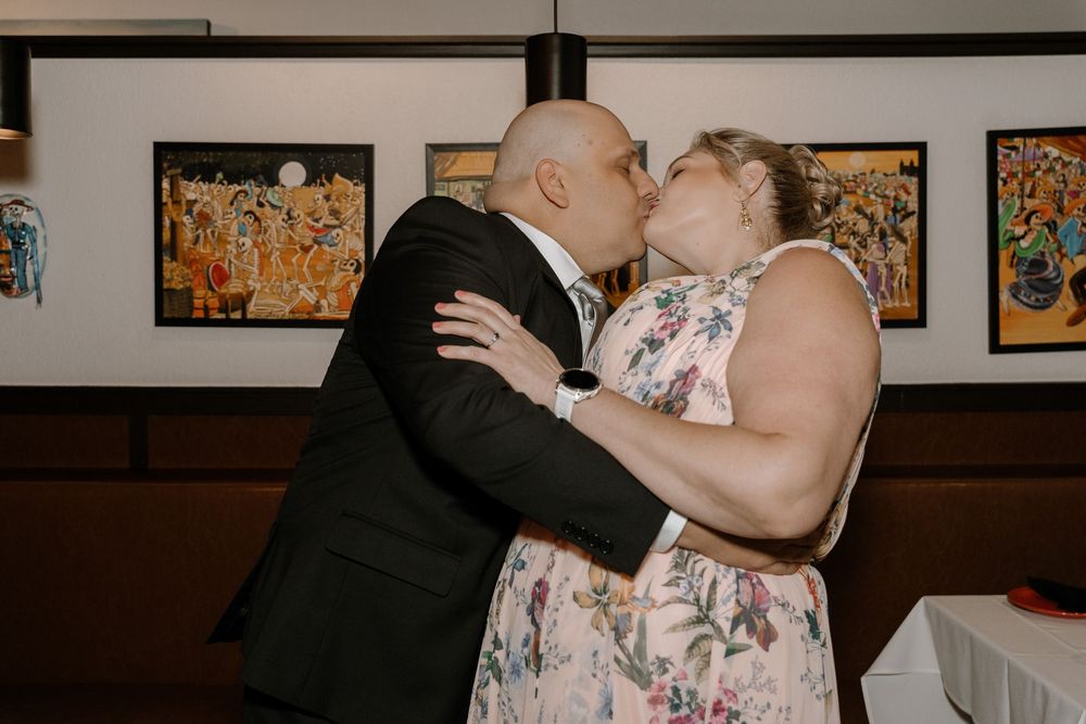 Couple sharing a romantic dance moment at an indoor reception venue with artwork displayed on walls.