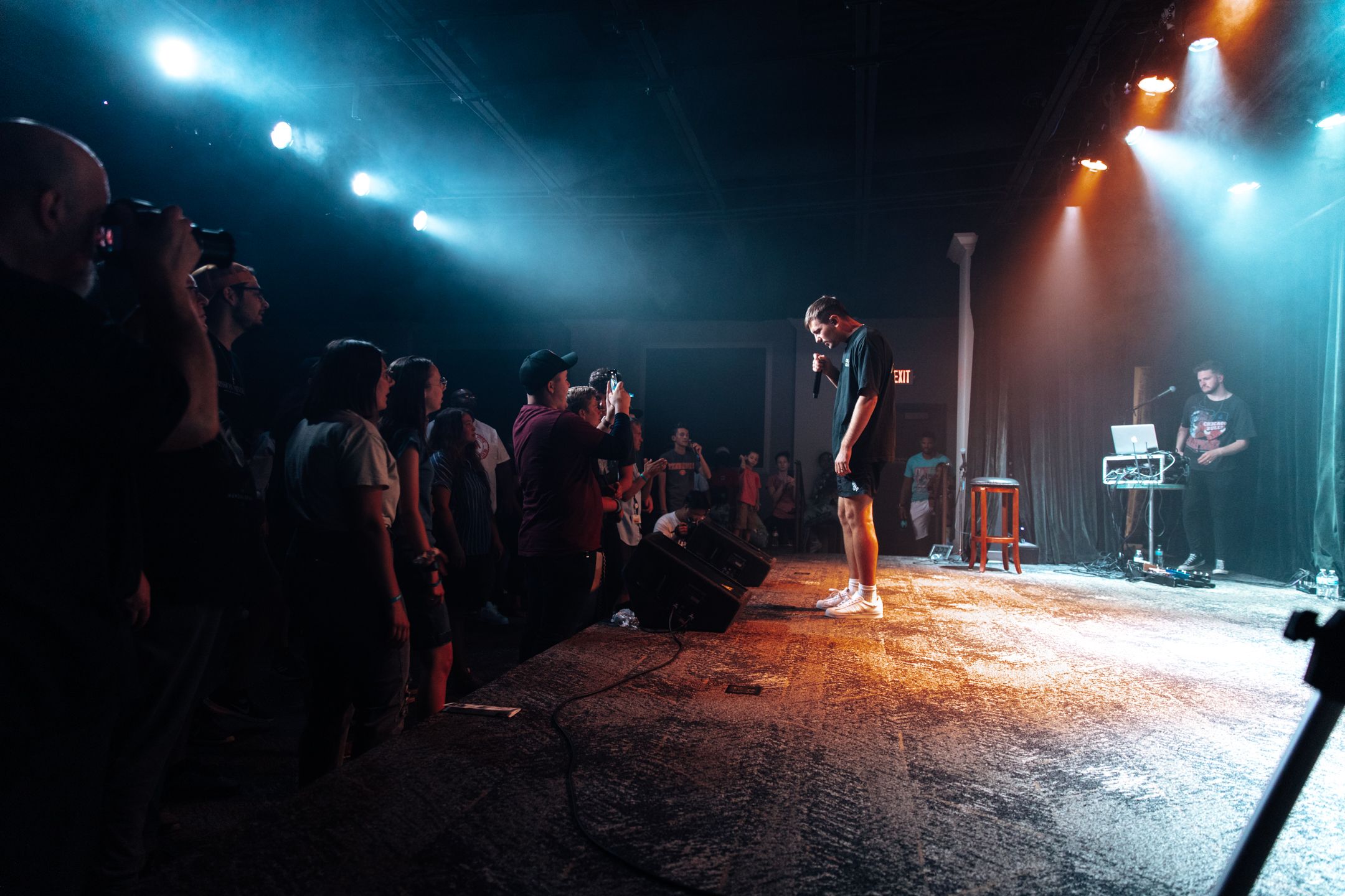 Dark concert venue with blue and orange stage lighting creating atmospheric effects.
