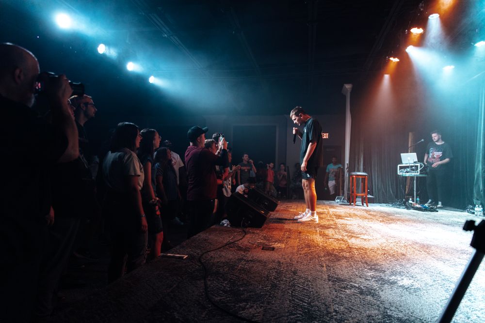 Dark concert venue with blue and orange stage lighting creating atmospheric effects.