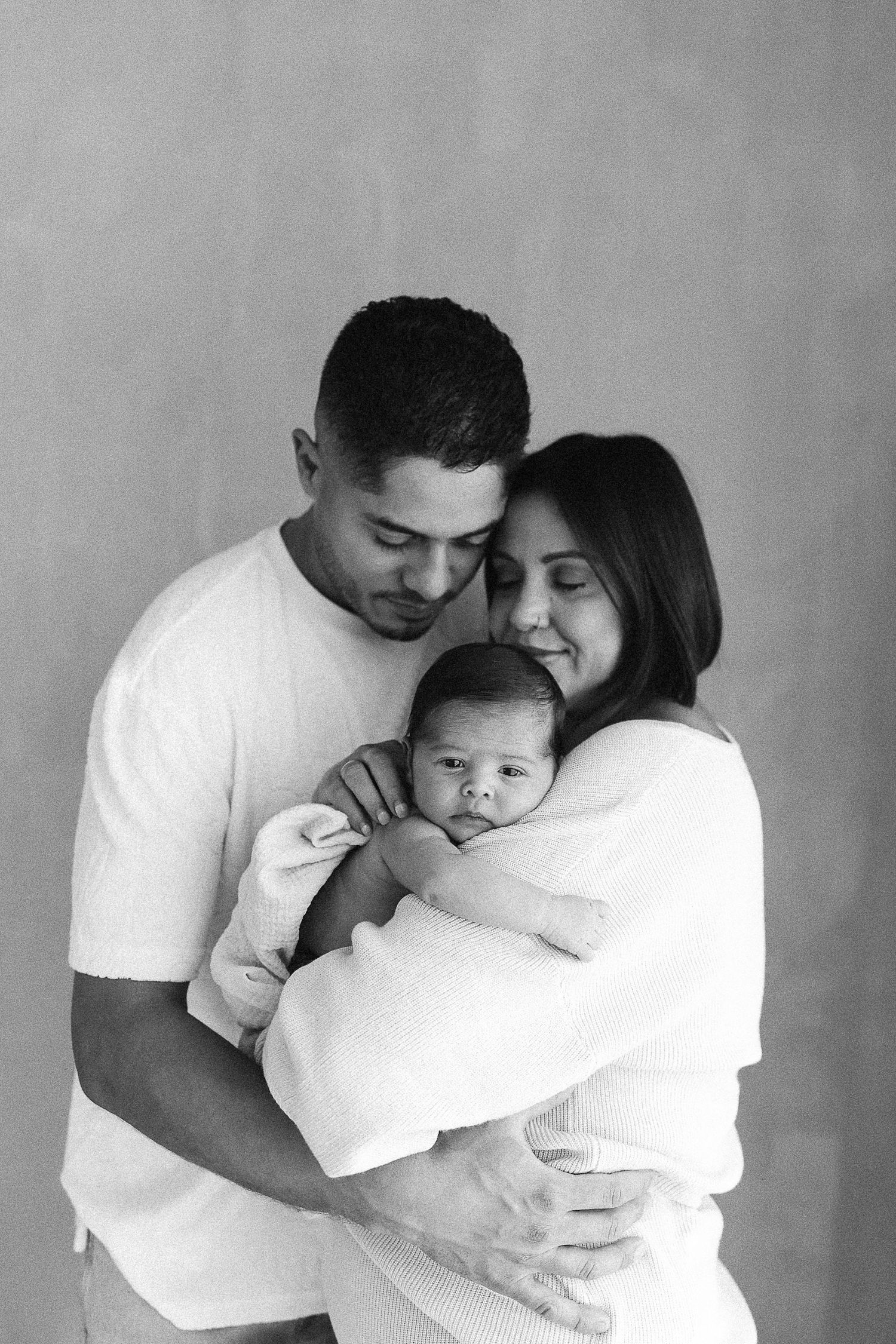 Family newborn photos with parents holding their baby during an Orange County studio session
