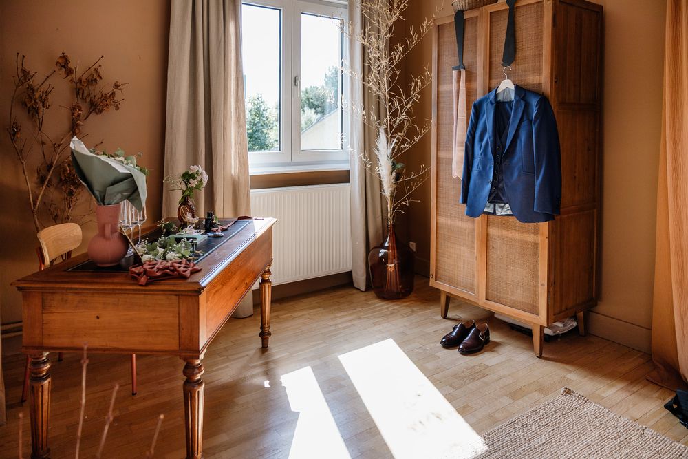 Photographe reportage mariage Lille : details du costume du marie dans une jolie piece baignee de lumiere pendant les preparatifs.