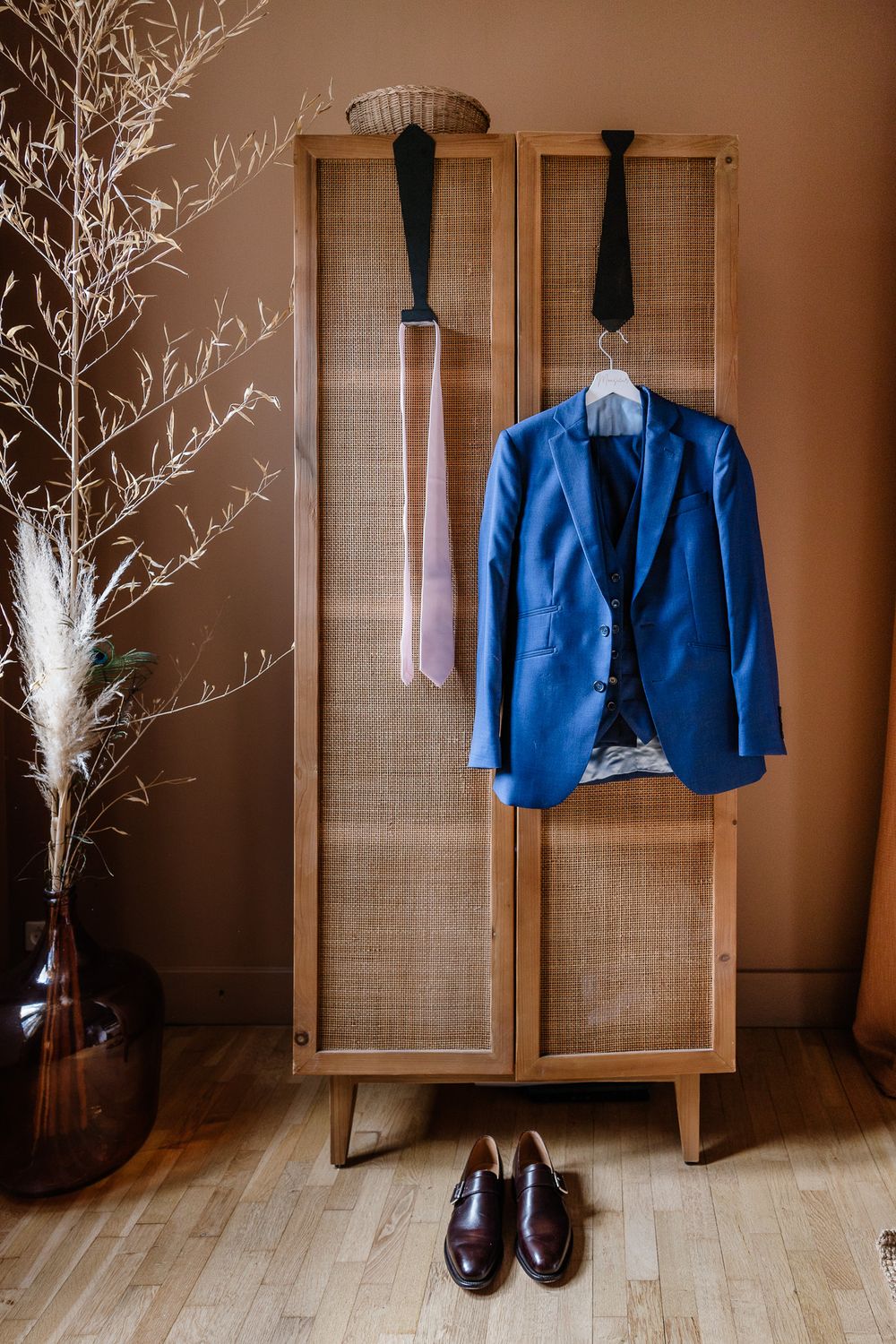 Costume bleu du marie pendu sur l'armoire de sa chambre elegante et rafinee, capture realisee pendant les preparatifs du marie en reportage.
