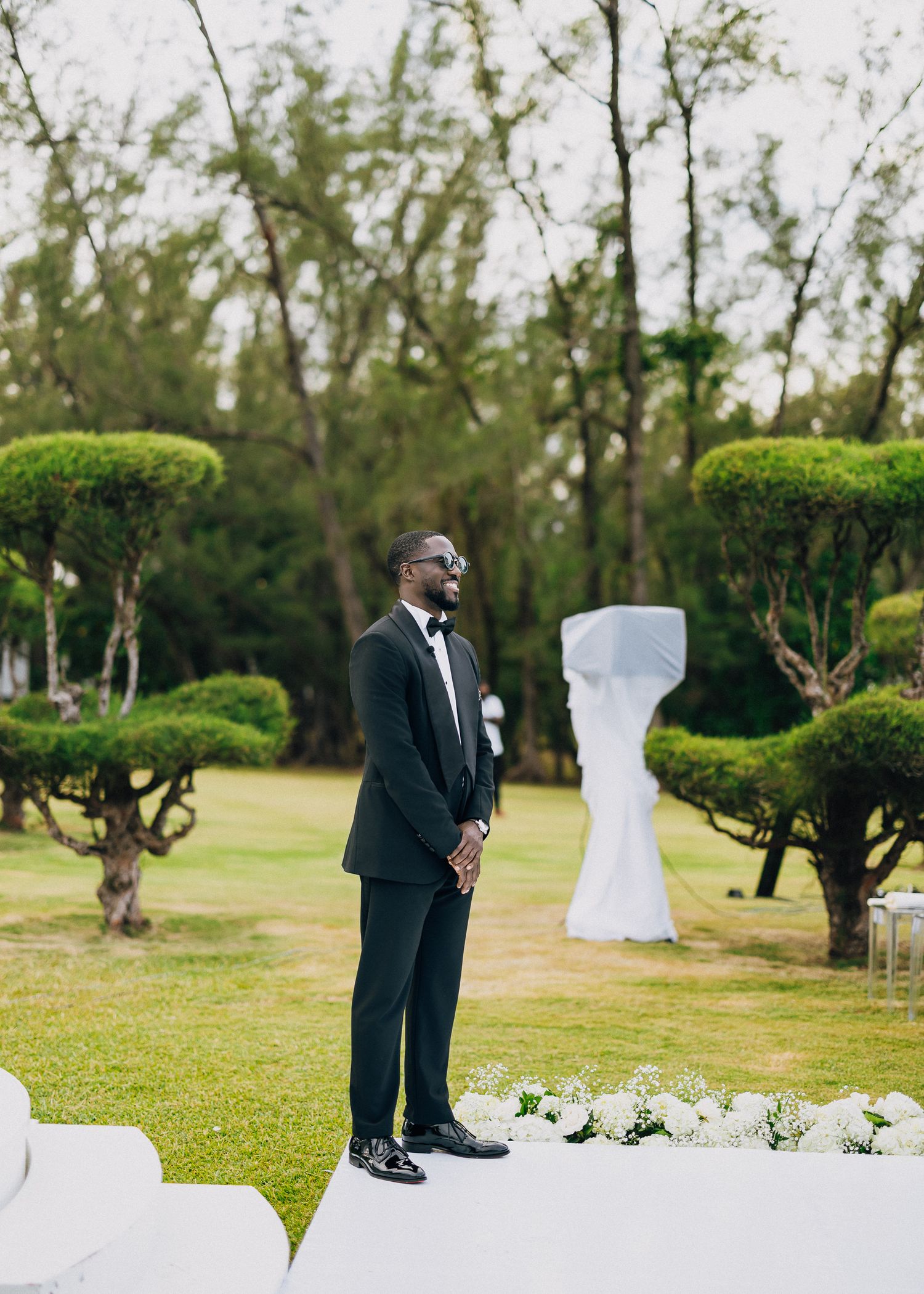 White floral wedding arch decorations line an outdoor ceremony space against a dark evening sky.