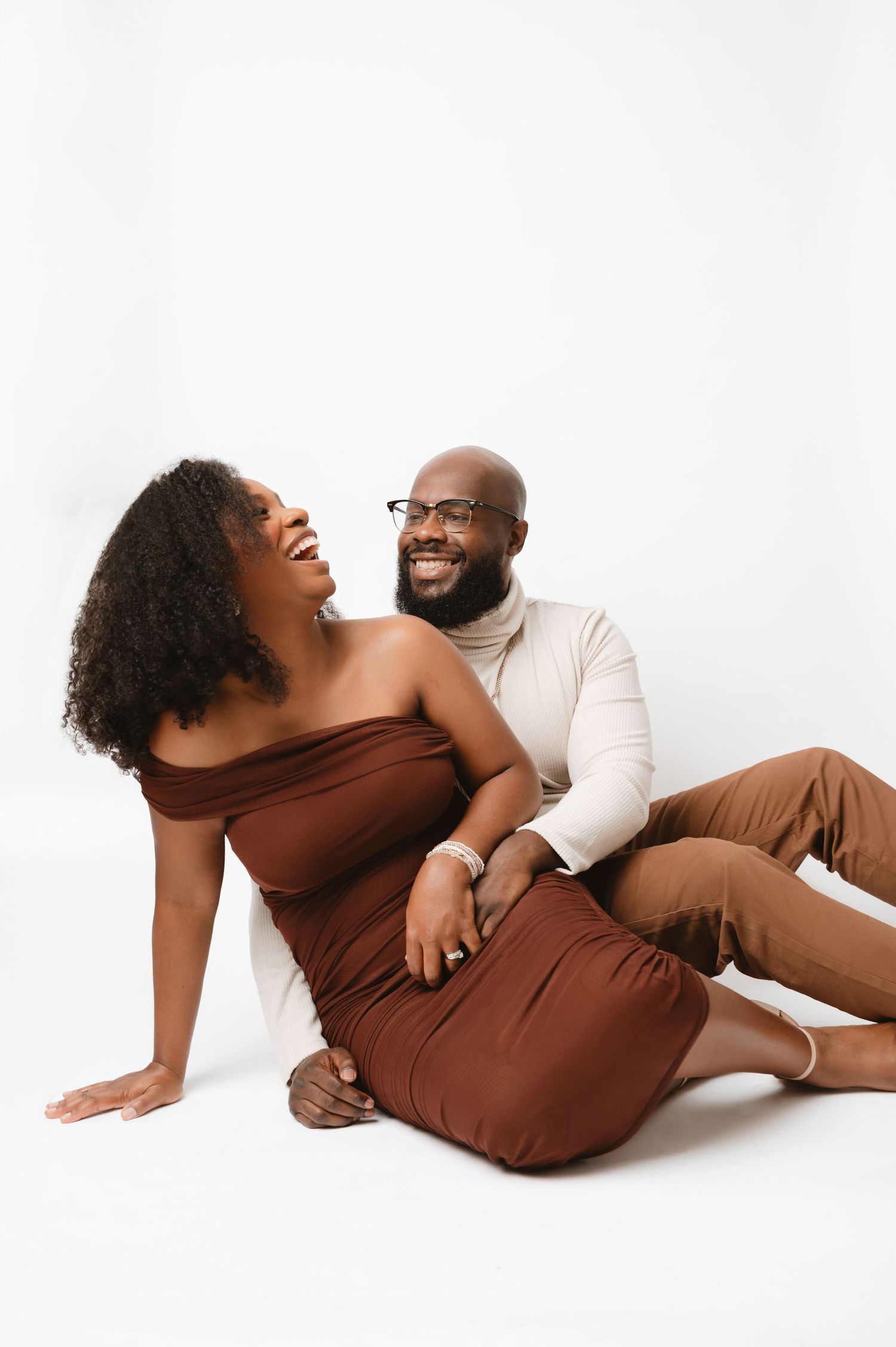 A couple in brown and white outfits shares intimate moments in a minimalist photo series against a white background.