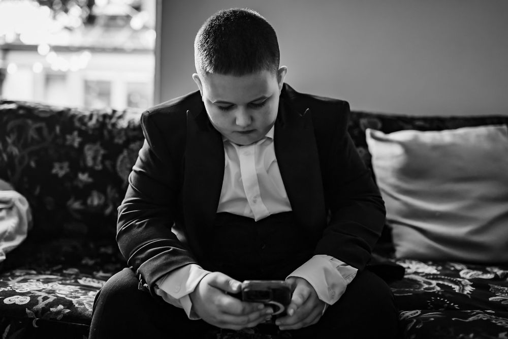 Black and white photo of someone looking down while seated in formal attire.
