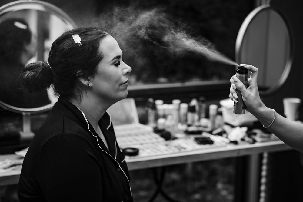 Black and white image of a person getting makeup applied in a professional setting.