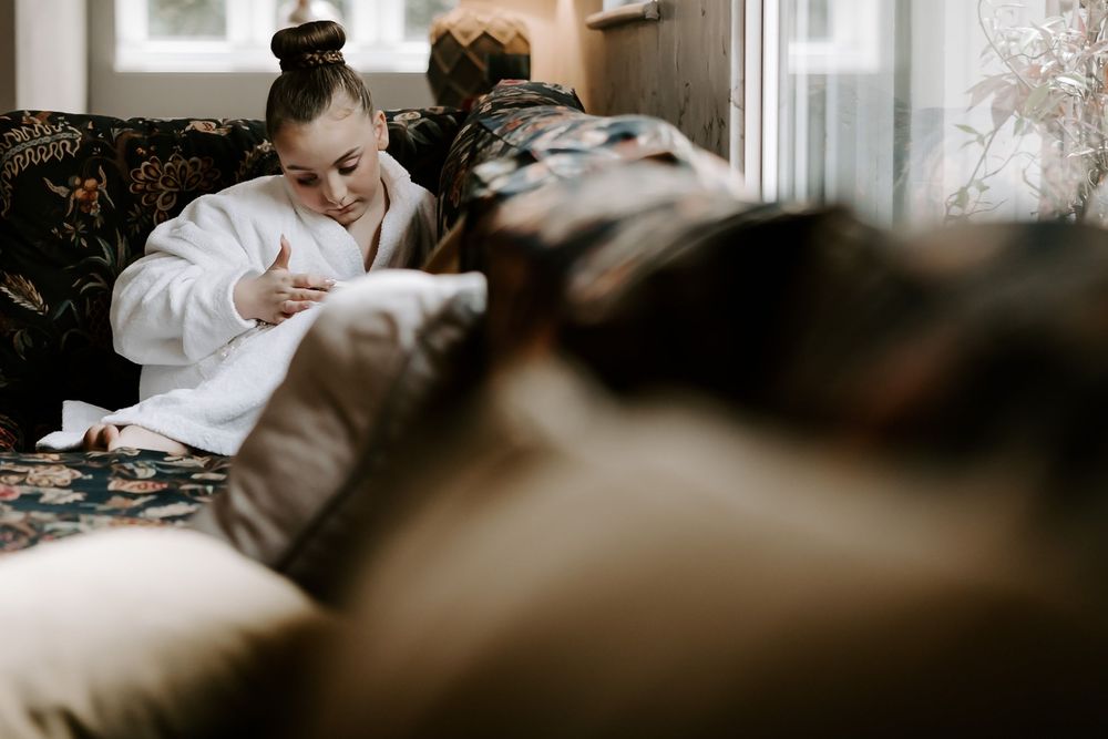 A person in a white bathrobe relaxes on a couch while looking at their phone in a cozy living room setting.