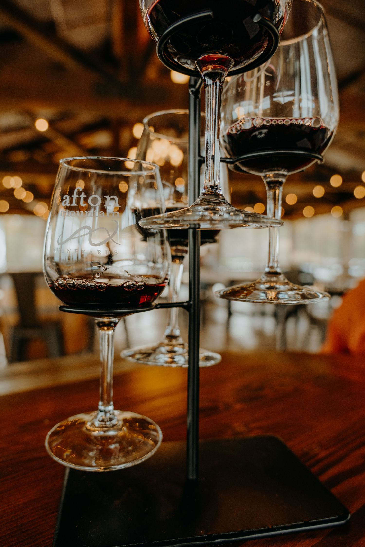 Close-up of wine glasses on wooden table with ambient lighting in rustic setting.