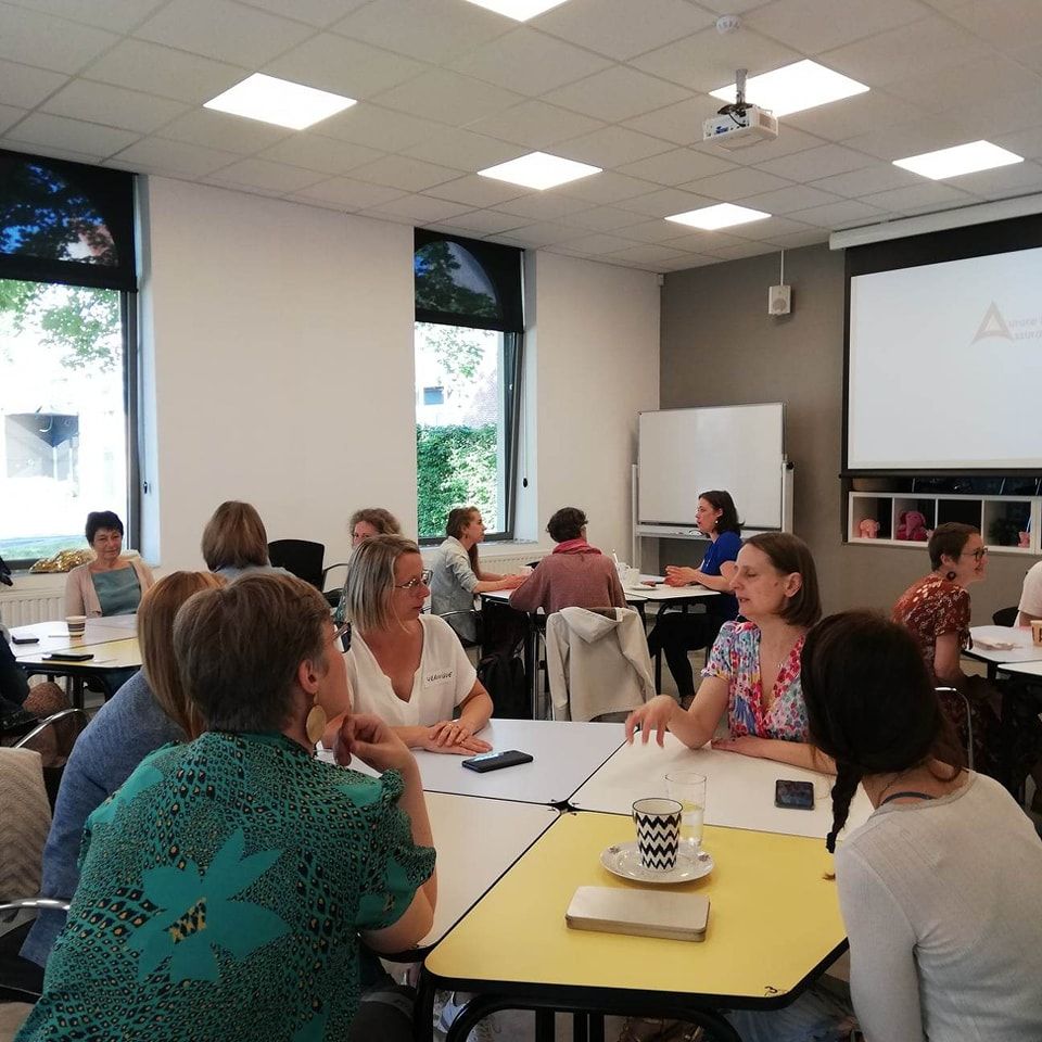 People sitting around tables in a classroom setting during what appears to be a training or educational session.