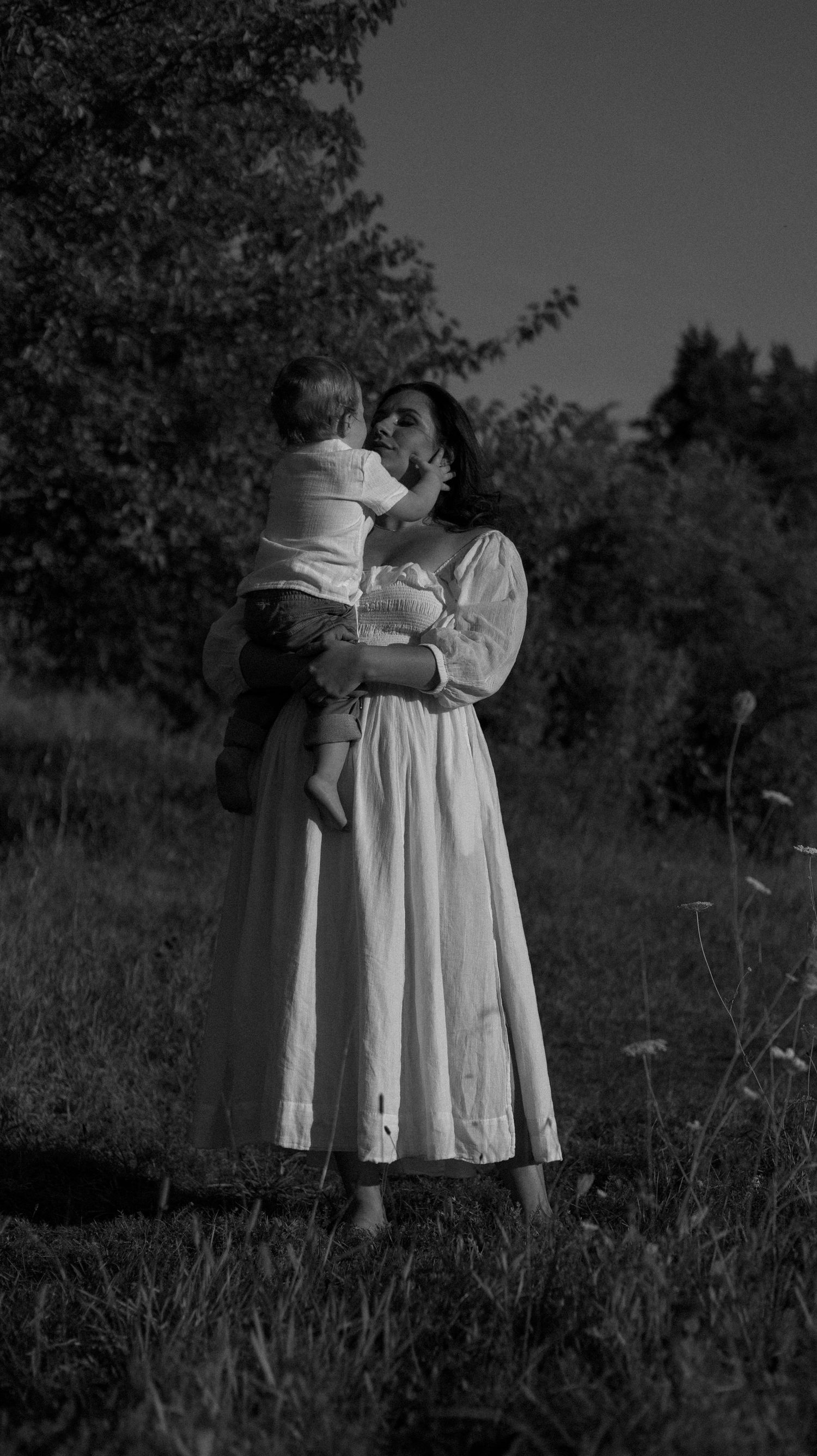 A series of black and white photographs showing two figures in white dresses embracing in a grassy field.