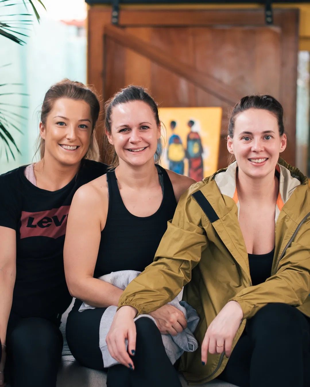 Group of smiling women sit together indoors, capturing friendship, warmth and community.