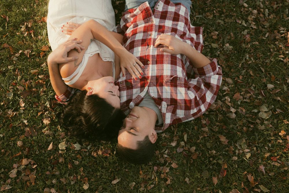 Intimate couple in casual attire sharing tender moments on grass.