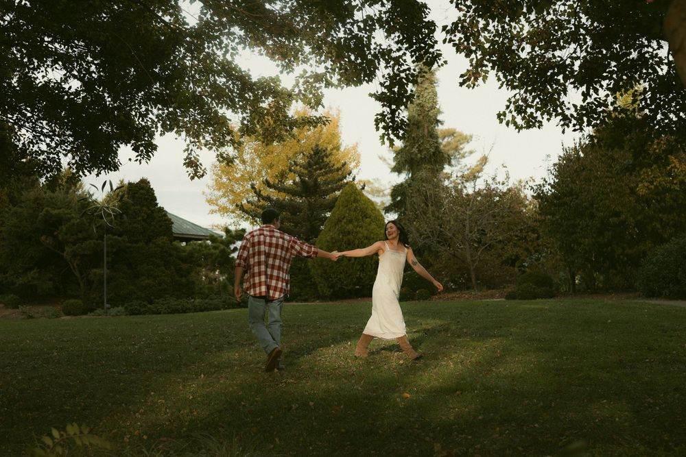 Dancing couple silhouetted against trees during sunset in a park.