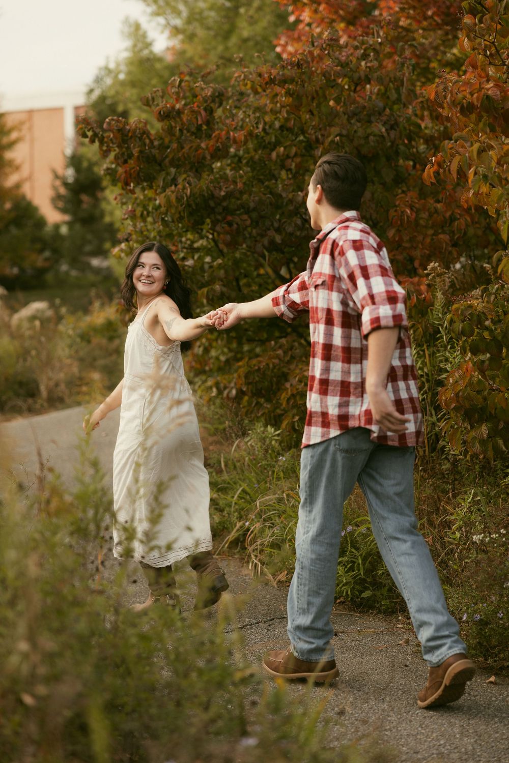 Playful couple dancing and spinning on a garden path in autumn.