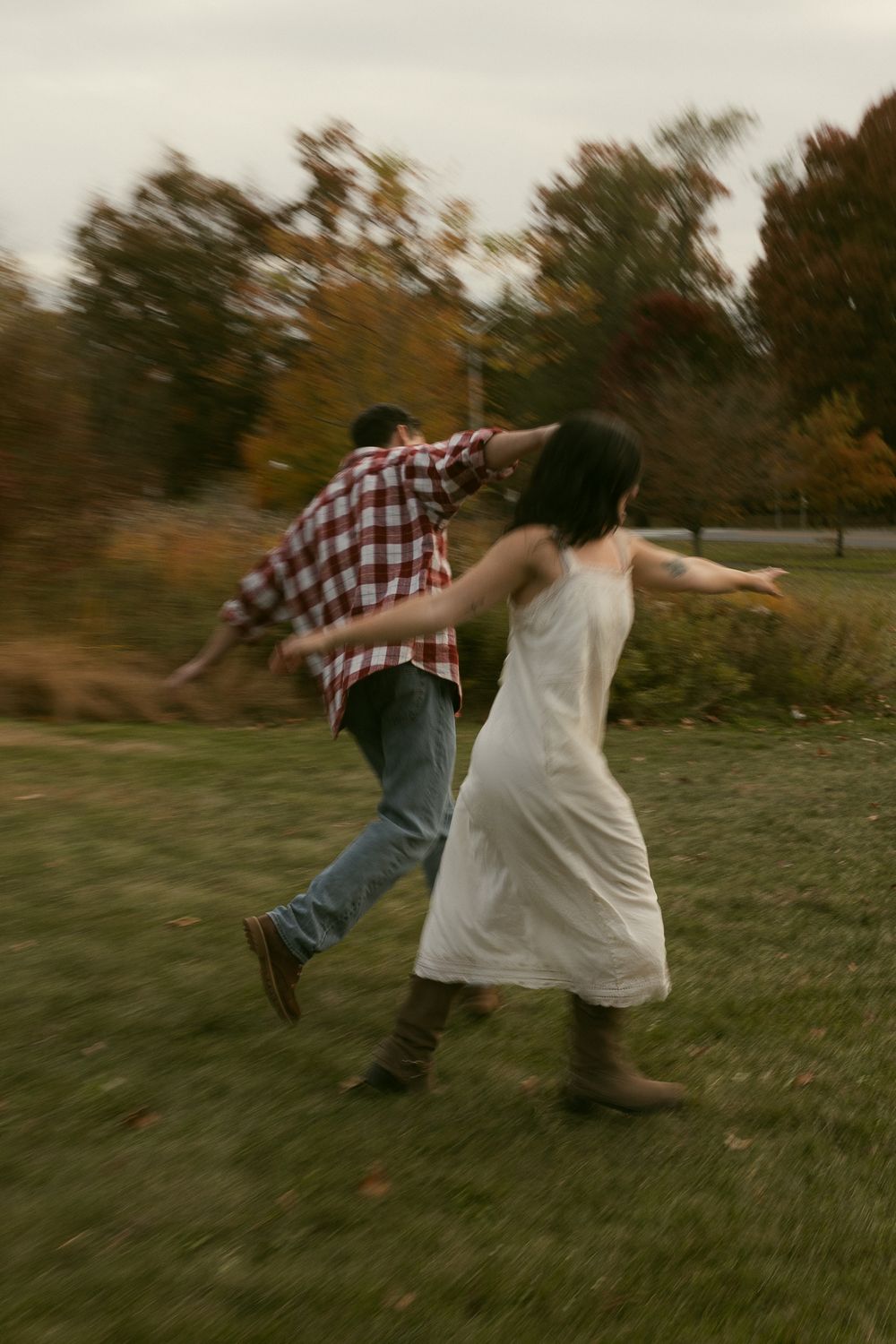 Couple dancing and spinning on grass during golden hour.