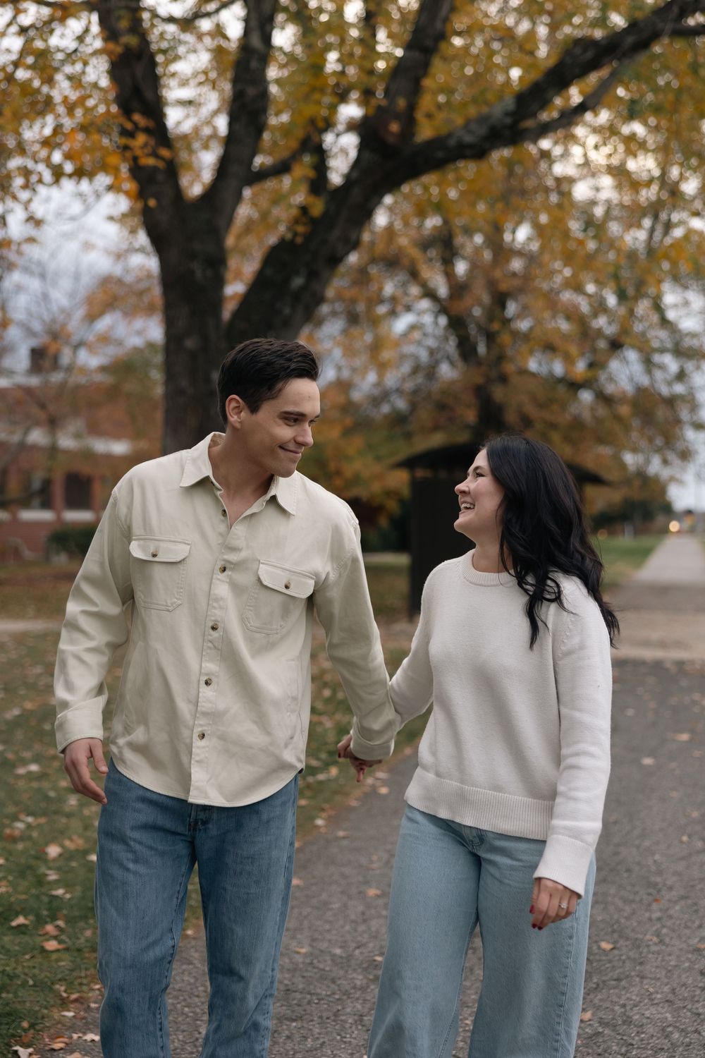 Autumn engagement photos with fallen leaves and casual outfits.