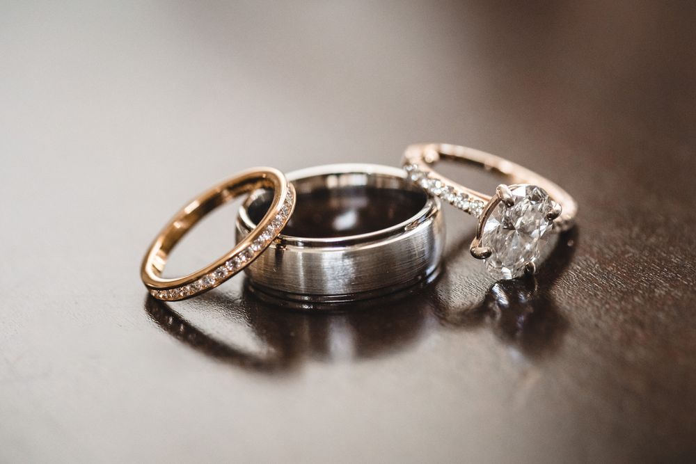 Close-up of wedding rings and bands arranged artistically on dark surface.