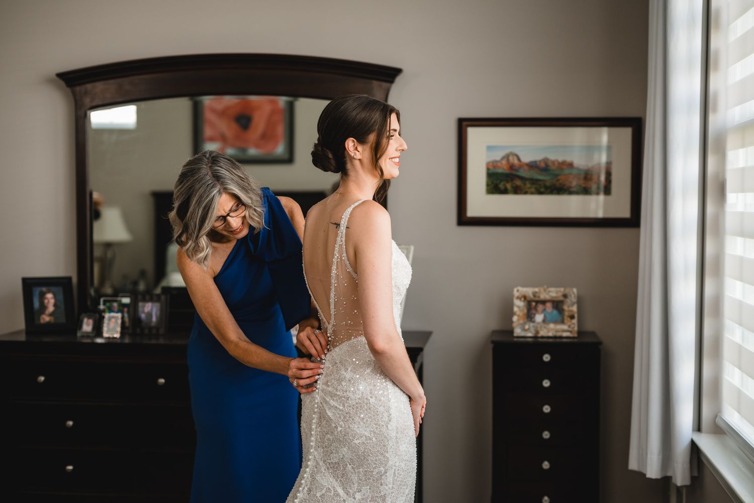 A tender embrace between a bride in a sequined dress and someone wearing navy blue in a bedroom setting.