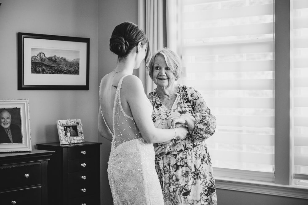A touching moment between a bride in white and someone in blue as they share an emotional embrace in a sunlit room.