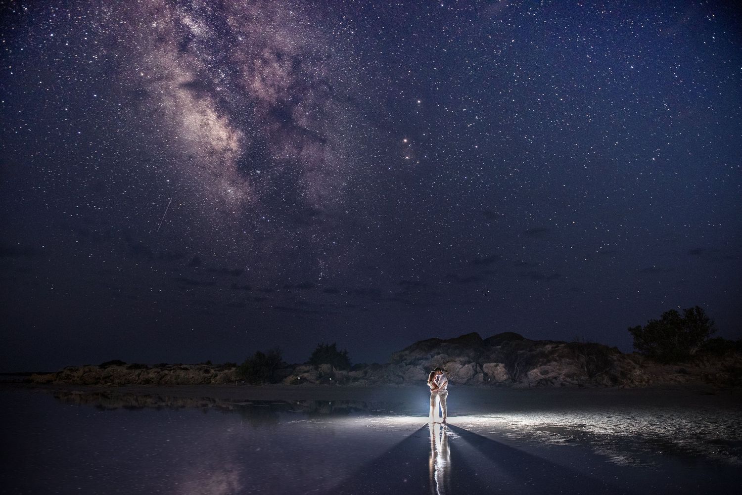 Ethereal nighttime wedding photography with starry sky and illuminated couple.