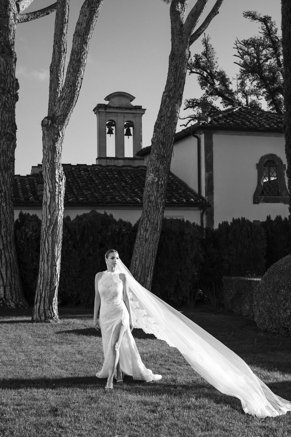 A dramatic black and white photo series showing a flowing wedding dress veil against tall pine trees.