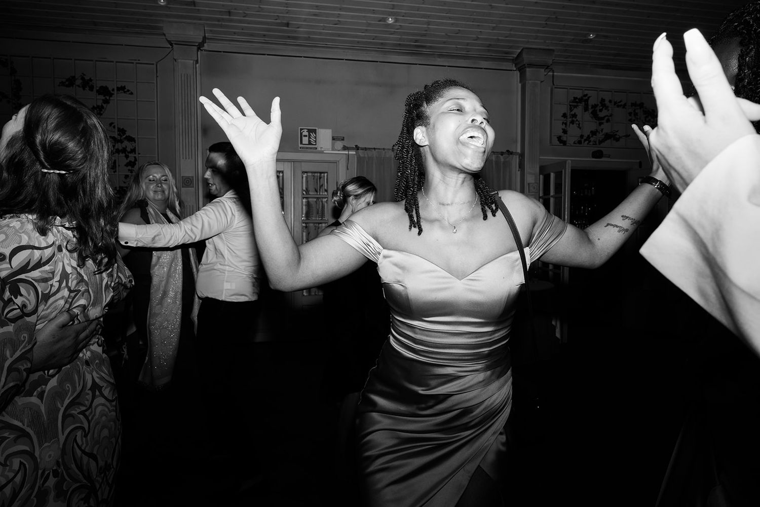 A group of people dancing and celebrating at a lively party with their hands raised in joyful movement.