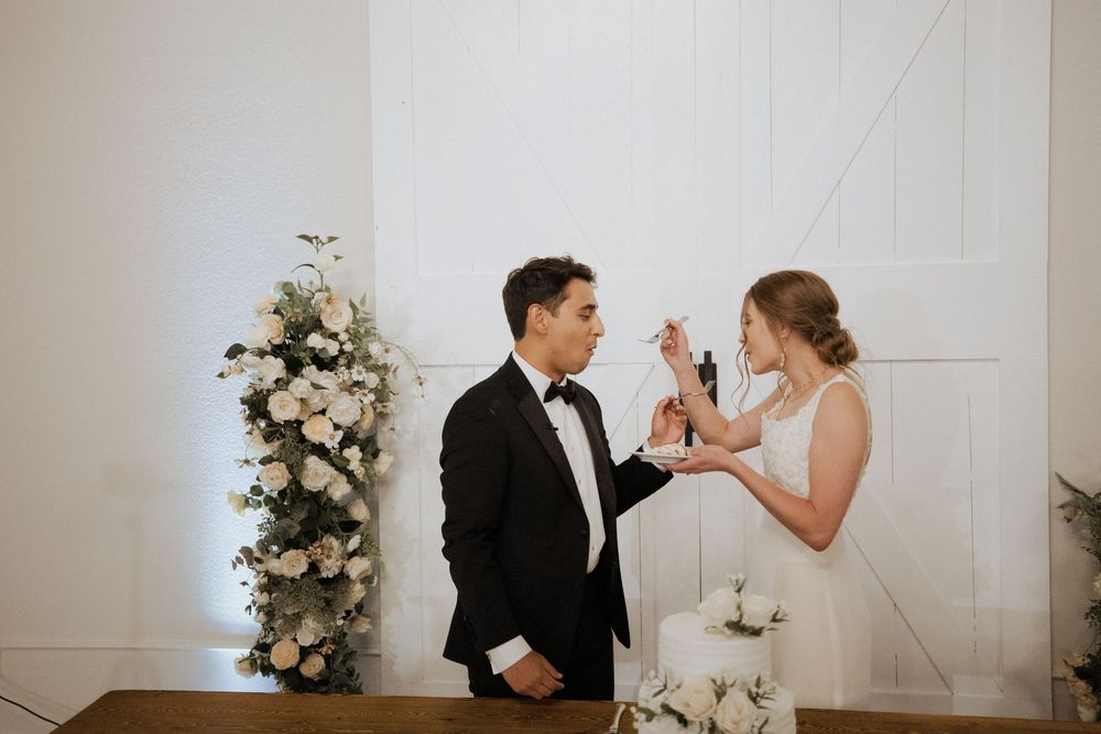 A bride and groom share an intimate moment feeding each other cake during their wedding reception.