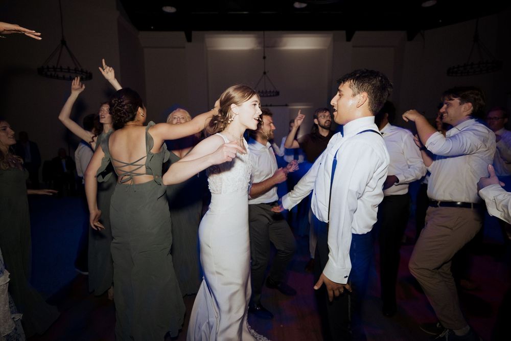 People dancing and celebrating at a lively party reception with dim lighting and energetic atmosphere.
